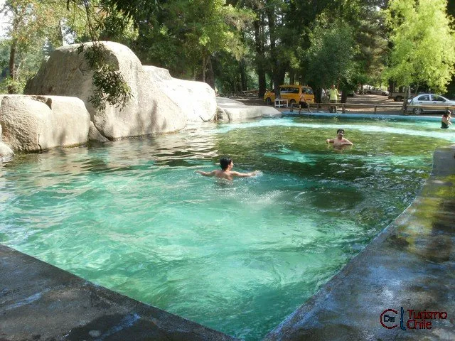 Piscina natural de roca con agua color esmeralda en el camping, turistas nadando