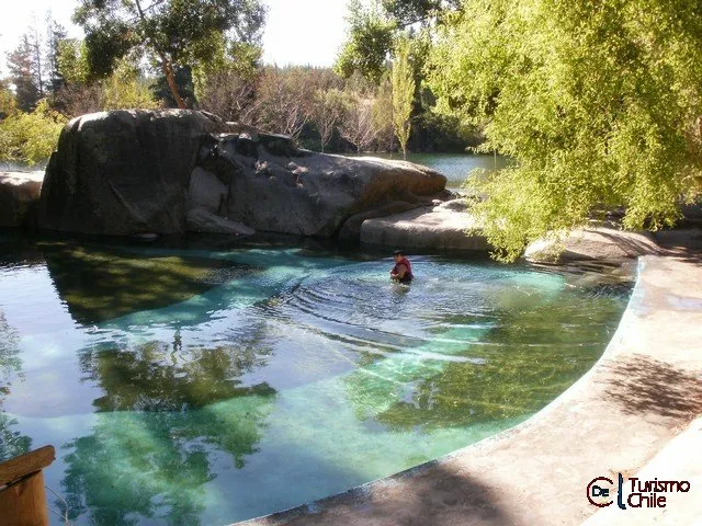 Piscina natural de roca con agua color esmeralda y turista nadando